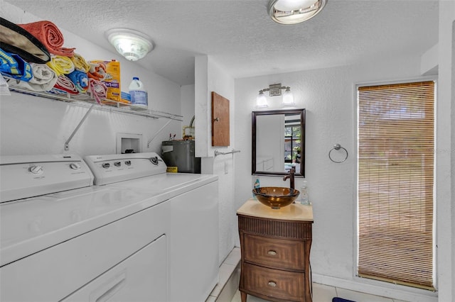 clothes washing area featuring a sink, a textured ceiling, water heater, a textured wall, and independent washer and dryer