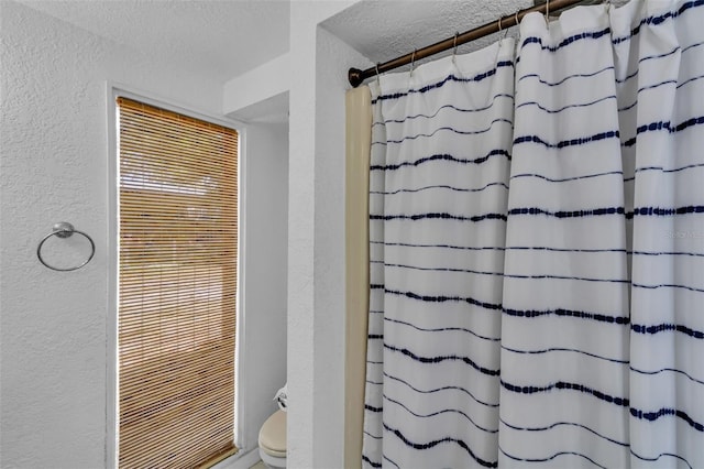 full bathroom with a textured wall, a shower with curtain, a textured ceiling, and toilet