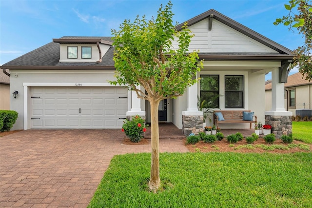 view of front of property with central air condition unit, an attached garage, decorative driveway, a front lawn, and covered porch