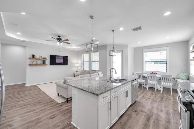 kitchen with visible vents, stainless steel appliances, a raised ceiling, a sink, and light wood-type flooring
