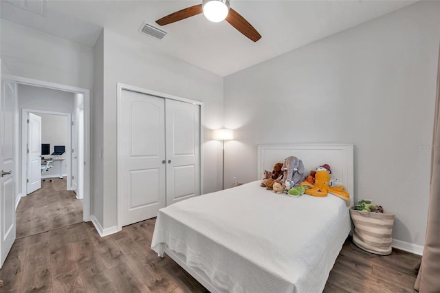 bedroom with baseboards, visible vents, wood finished floors, and a closet