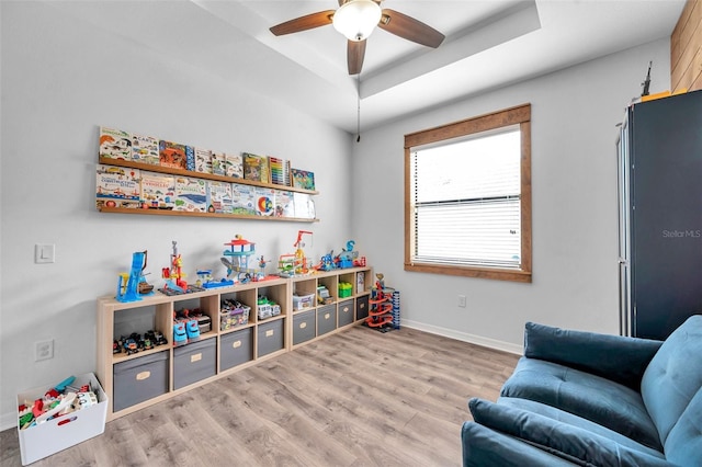 recreation room featuring baseboards, wood finished floors, ceiling fan, and a raised ceiling