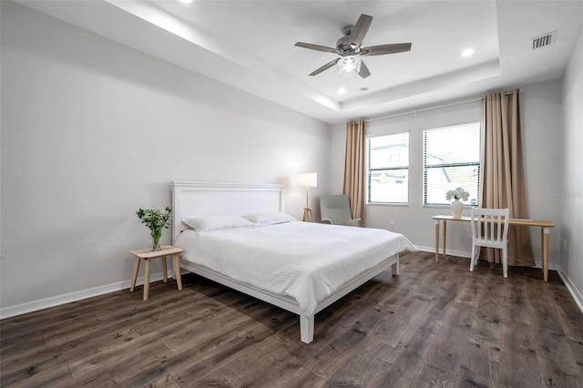 bedroom featuring recessed lighting, a tray ceiling, baseboards, and dark wood-type flooring