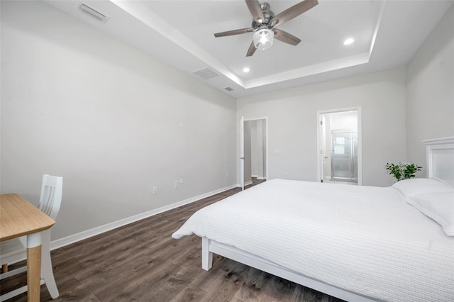 bedroom featuring a tray ceiling, recessed lighting, baseboards, visible vents, and wood finished floors