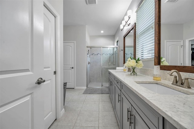 bathroom with tile patterned flooring, vanity, baseboards, a stall shower, and visible vents