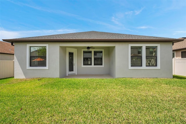 back of house with a lawn, ceiling fan, fence, and stucco siding