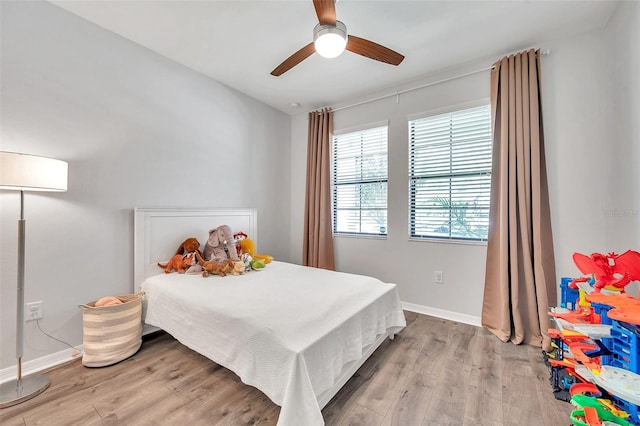 bedroom with a ceiling fan, baseboards, and light wood finished floors