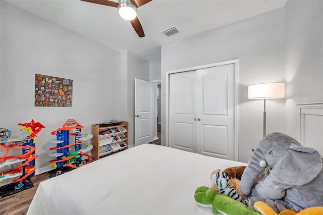 bedroom with a closet, a ceiling fan, wood finished floors, baseboards, and visible vents
