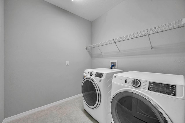 clothes washing area featuring washing machine and dryer, baseboards, and laundry area