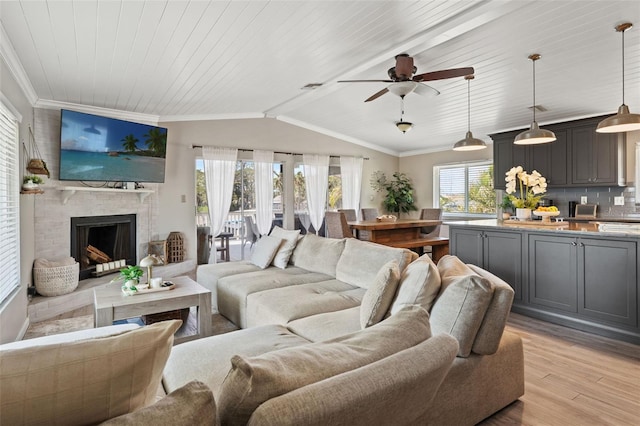 living room featuring a ceiling fan, light wood-style floors, crown molding, and lofted ceiling