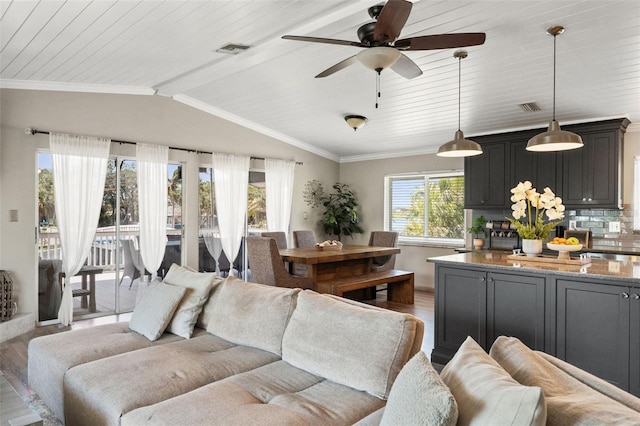 living room featuring visible vents, light wood-style flooring, and vaulted ceiling
