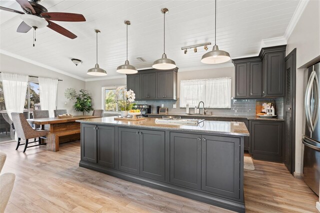 kitchen with stainless steel refrigerator, ornamental molding, a sink, and a kitchen island