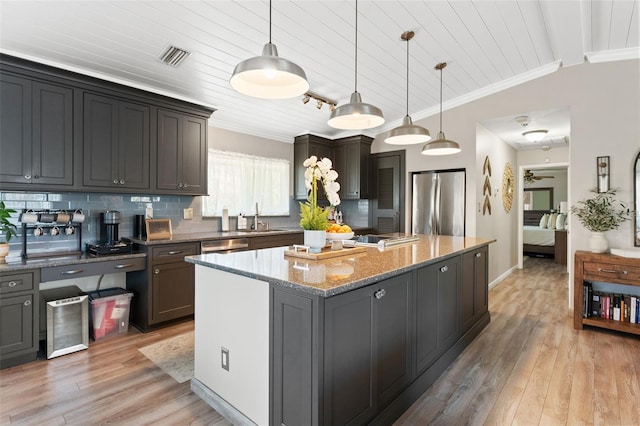 kitchen with a center island, a sink, tasteful backsplash, and appliances with stainless steel finishes