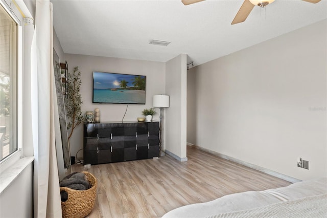 living area with plenty of natural light, visible vents, wood finished floors, and ceiling fan