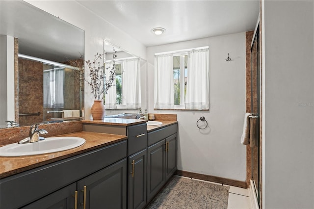 bathroom with a shower stall, double vanity, a sink, and tile patterned floors