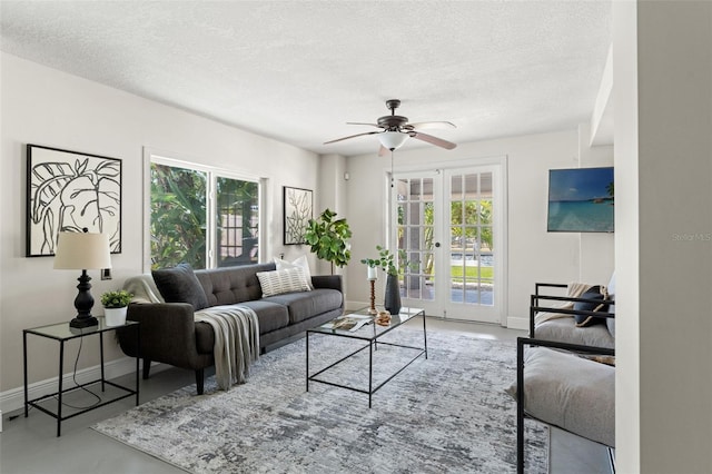 living room featuring a textured ceiling, baseboards, ceiling fan, finished concrete floors, and french doors