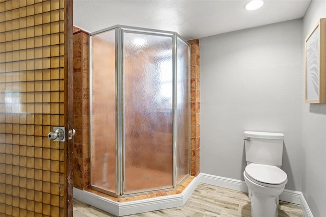 full bathroom featuring recessed lighting, toilet, baseboards, a stall shower, and wood finished floors