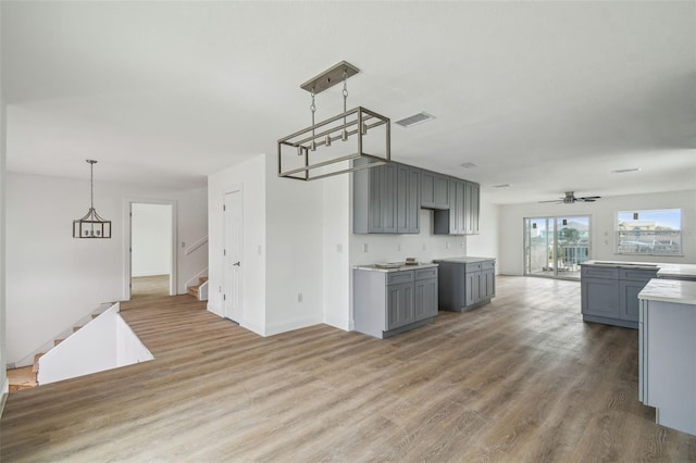 15621 Bertram Dr, Hudson, FL 34667 - kitchen with gray cabinets, wood finished floors, decorative light fixtures, and a ceiling fan