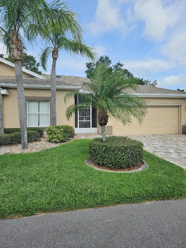 607 Manchester Woods Dr Unit 84, Sun City Center, FL 33573 - view of front facade with stucco siding, driveway, an attached garage, and a front lawn