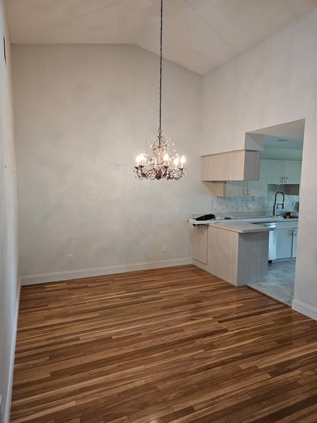 607 Manchester Woods Dr Unit 84, Sun City Center, FL 33573 - unfurnished dining area featuring wood finished floors, baseboards, a chandelier, high vaulted ceiling, and a sink