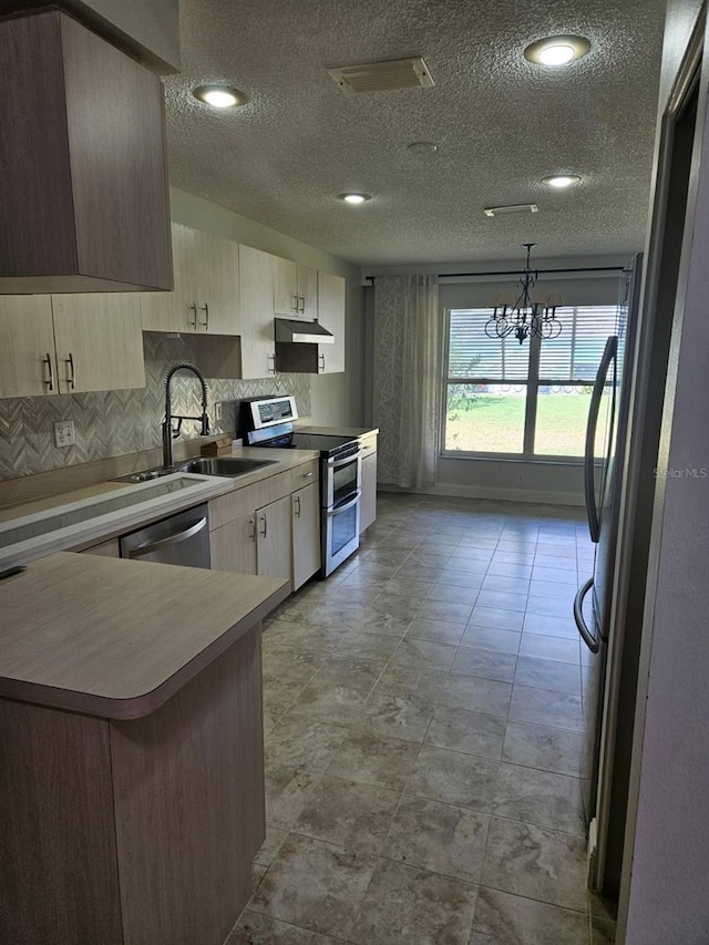 607 Manchester Woods Dr Unit 84, Sun City Center, FL 33573 - kitchen featuring stainless steel appliances, under cabinet range hood, a sink, a chandelier, and a textured ceiling
