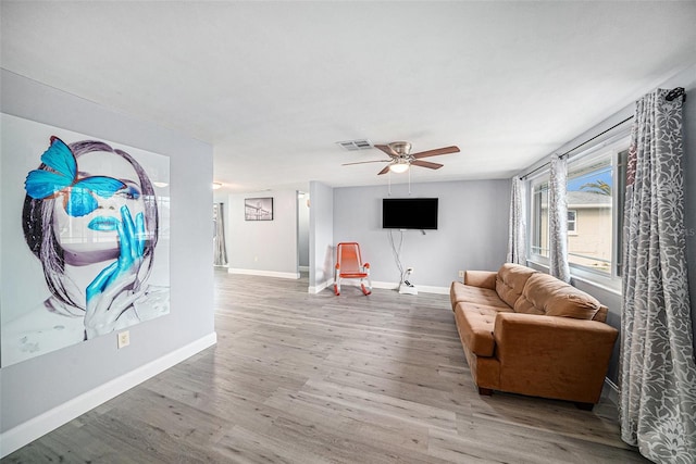 living area with baseboards, visible vents, a ceiling fan, and wood finished floors