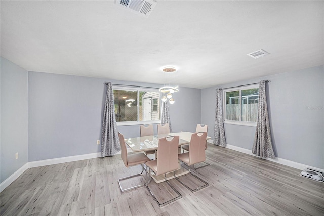 unfurnished dining area featuring wood finished floors, a notable chandelier, baseboards, and visible vents
