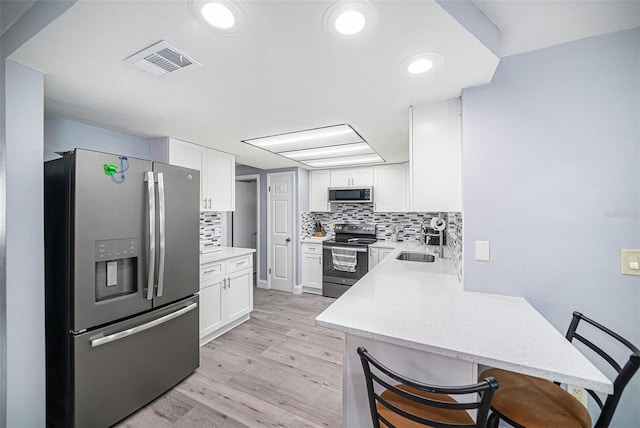 kitchen featuring visible vents, backsplash, white cabinetry, and stainless steel appliances