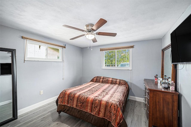 bedroom with baseboards, wood finished floors, ceiling fan, and a textured ceiling