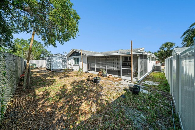 back of house featuring a sunroom, a fenced backyard, an outdoor structure, and a shed