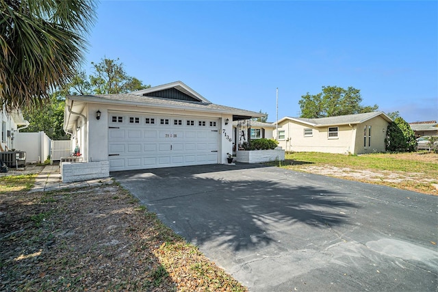 ranch-style house with driveway, stucco siding, fence, a garage, and central AC