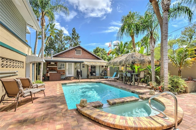 921 24th Ave N, Saint Petersburg, FL 33704 - view of swimming pool featuring a patio, a pool with connected hot tub, an exterior structure, and an outbuilding