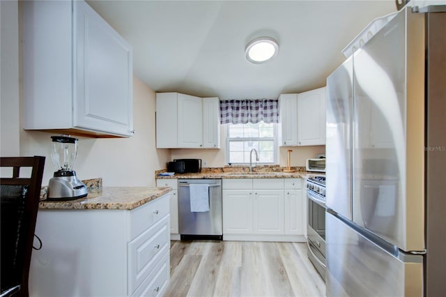 921 24th Ave N, Saint Petersburg, FL 33704 - kitchen featuring stainless steel appliances, a sink, light wood-style floors, white cabinets, and light stone counters
