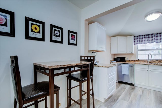 921 24th Ave N, Saint Petersburg, FL 33704 - kitchen featuring stainless steel dishwasher, a sink, light wood finished floors, white cabinets, and light stone counters