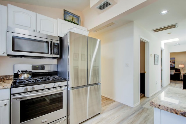 921 24th Ave N, Saint Petersburg, FL 33704 - kitchen featuring stainless steel appliances, light wood-style flooring, light stone counters, white cabinets, and baseboards