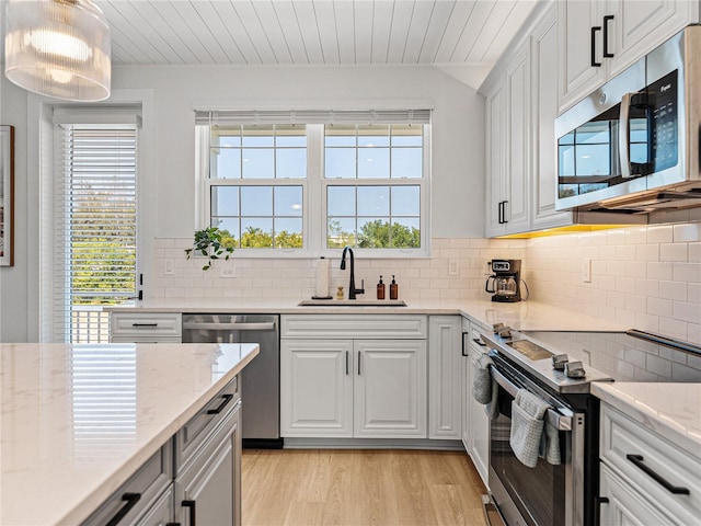 4215 Saltwater Pearl Way, Cortez, FL 34215 - kitchen featuring stainless steel appliances, light wood finished floors, decorative backsplash, white cabinets, and light stone countertops