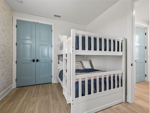 4215 Saltwater Pearl Way, Cortez, FL 34215 - bedroom with wood finished floors, wallpapered walls, a closet, and lofted ceiling