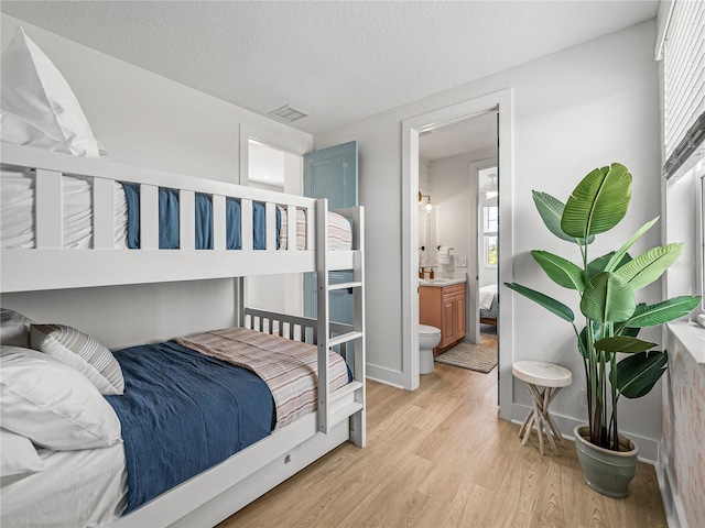 4215 Saltwater Pearl Way, Cortez, FL 34215 - bedroom with light wood-style floors, connected bathroom, and a textured ceiling