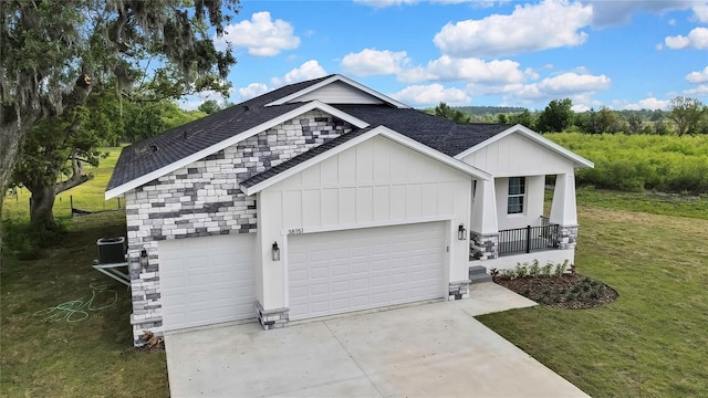 view of front facade with concrete driveway, roof with shingles, an attached garage, stone siding, and a front lawn