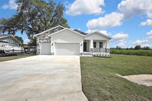 view of front of house featuring stone siding, driveway, a front lawn, a porch, and a garage