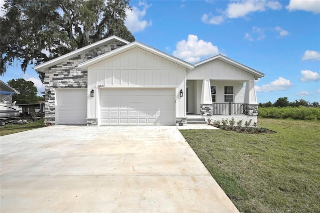 view of front of home with driveway, a front yard, covered porch, stone siding, and an attached garage