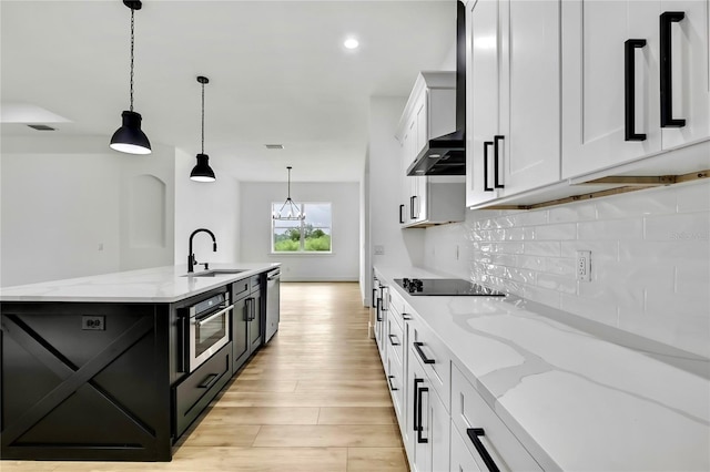 kitchen featuring backsplash, a sink, appliances with stainless steel finishes, light wood-type flooring, and decorative light fixtures