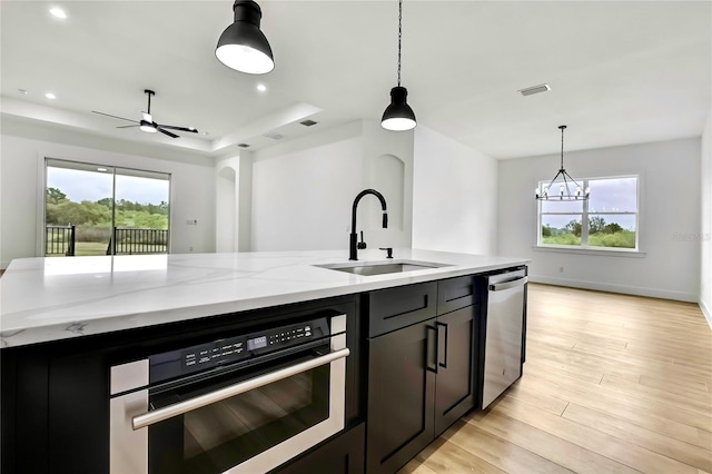 kitchen with visible vents, light wood-style flooring, light stone countertops, appliances with stainless steel finishes, and a sink