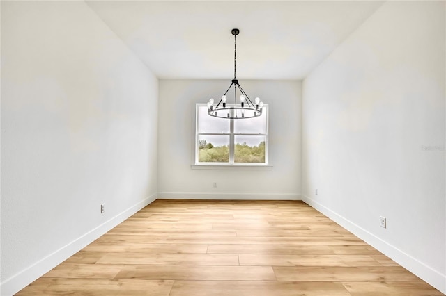 unfurnished dining area with baseboards, a chandelier, and light wood-type flooring