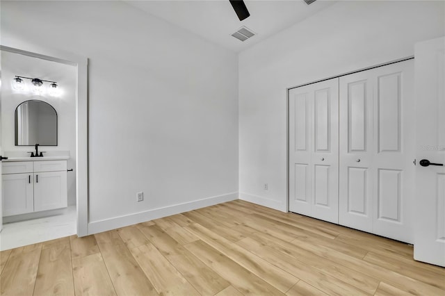 unfurnished bedroom featuring baseboards, a sink, connected bathroom, visible vents, and light wood-style flooring