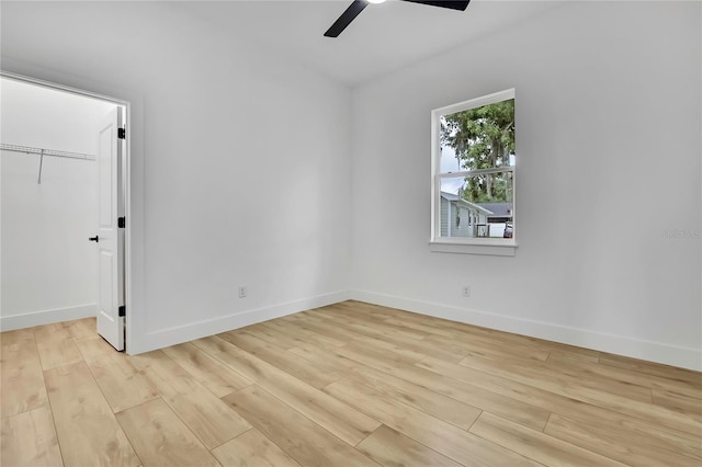 empty room featuring baseboards, light wood-style floors, and ceiling fan