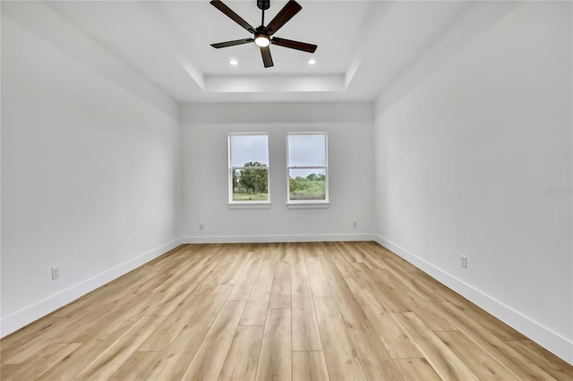 empty room featuring a tray ceiling, a ceiling fan, light wood-type flooring, baseboards, and recessed lighting