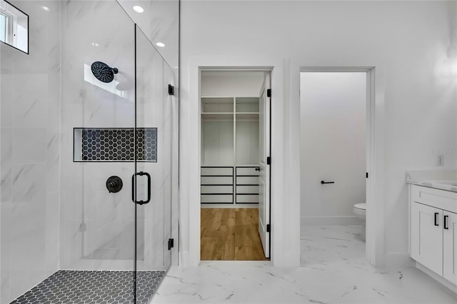 bathroom featuring vanity, marble finish floor, toilet, and a shower stall