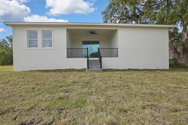 rear view of property with stucco siding, ceiling fan, a porch, and a yard
