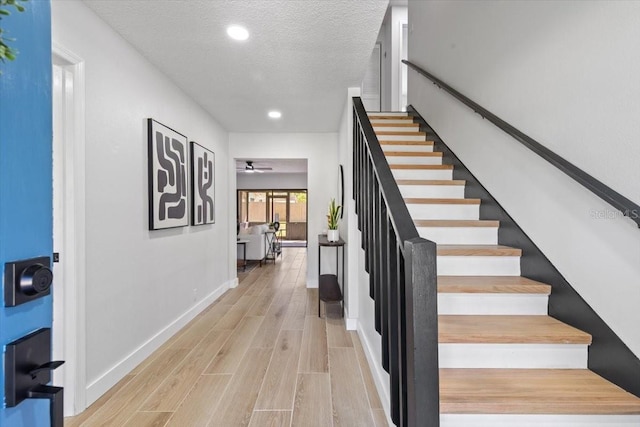 stairs featuring baseboards, recessed lighting, a textured ceiling, a ceiling fan, and wood finished floors